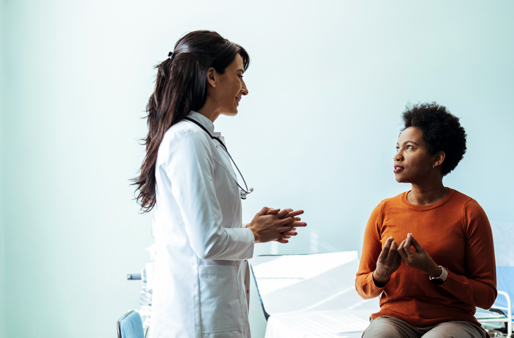 Standing doctor talks to a sitting patient.